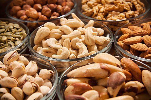 Les récipients contiennent des noix, des noisettes, des noix de cajou, des amandes, des noix du brésil, des pistaches et graines de tournesols.